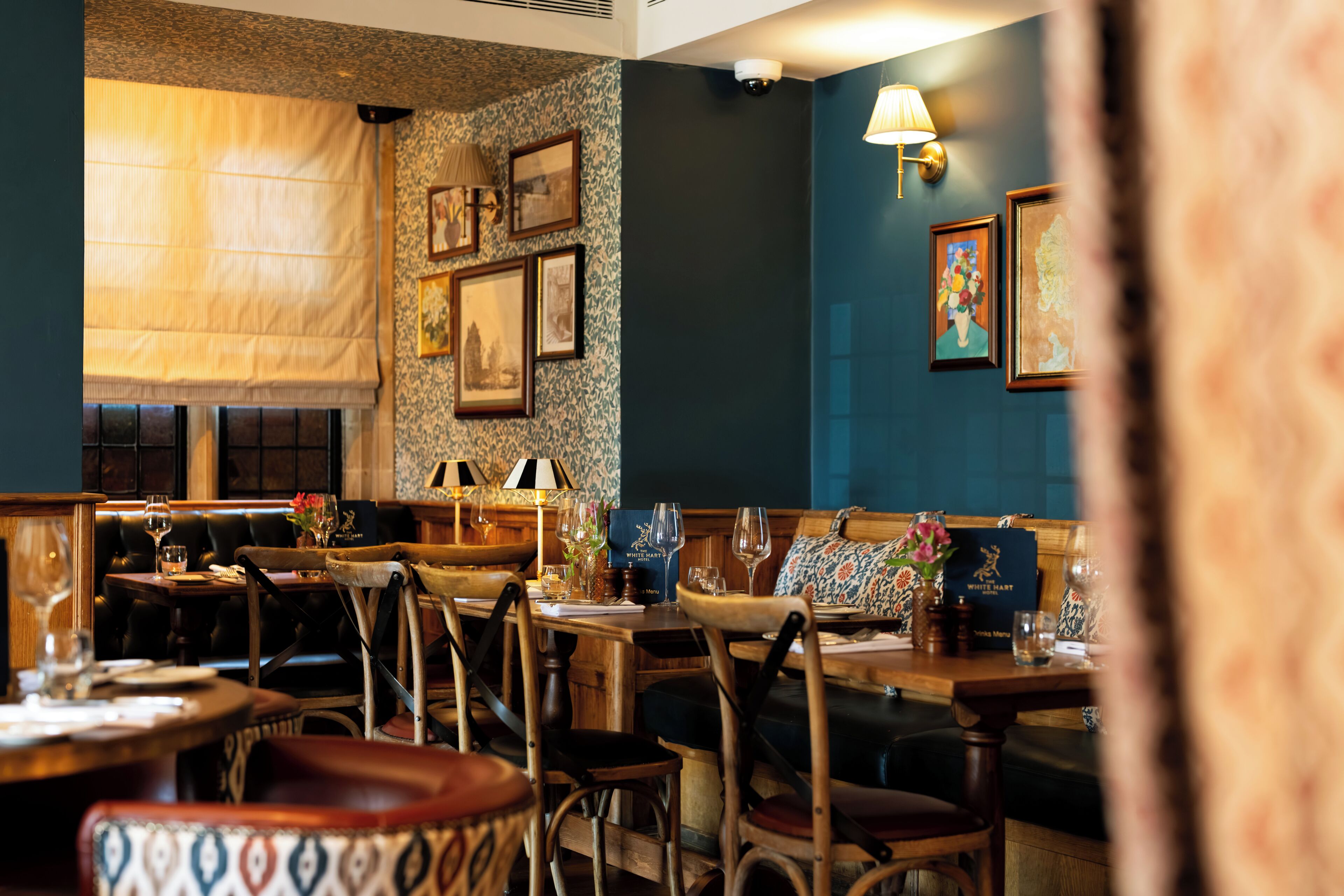 Interior de restaurante com mobiliário de madeira, quadros nas paredes e uma mesa posta para refeição.