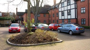 A parking area with several cars, a tree, and a building with a mix of brick and timber framing. - The White Hart Hotel (Kingston Upon Thames)
