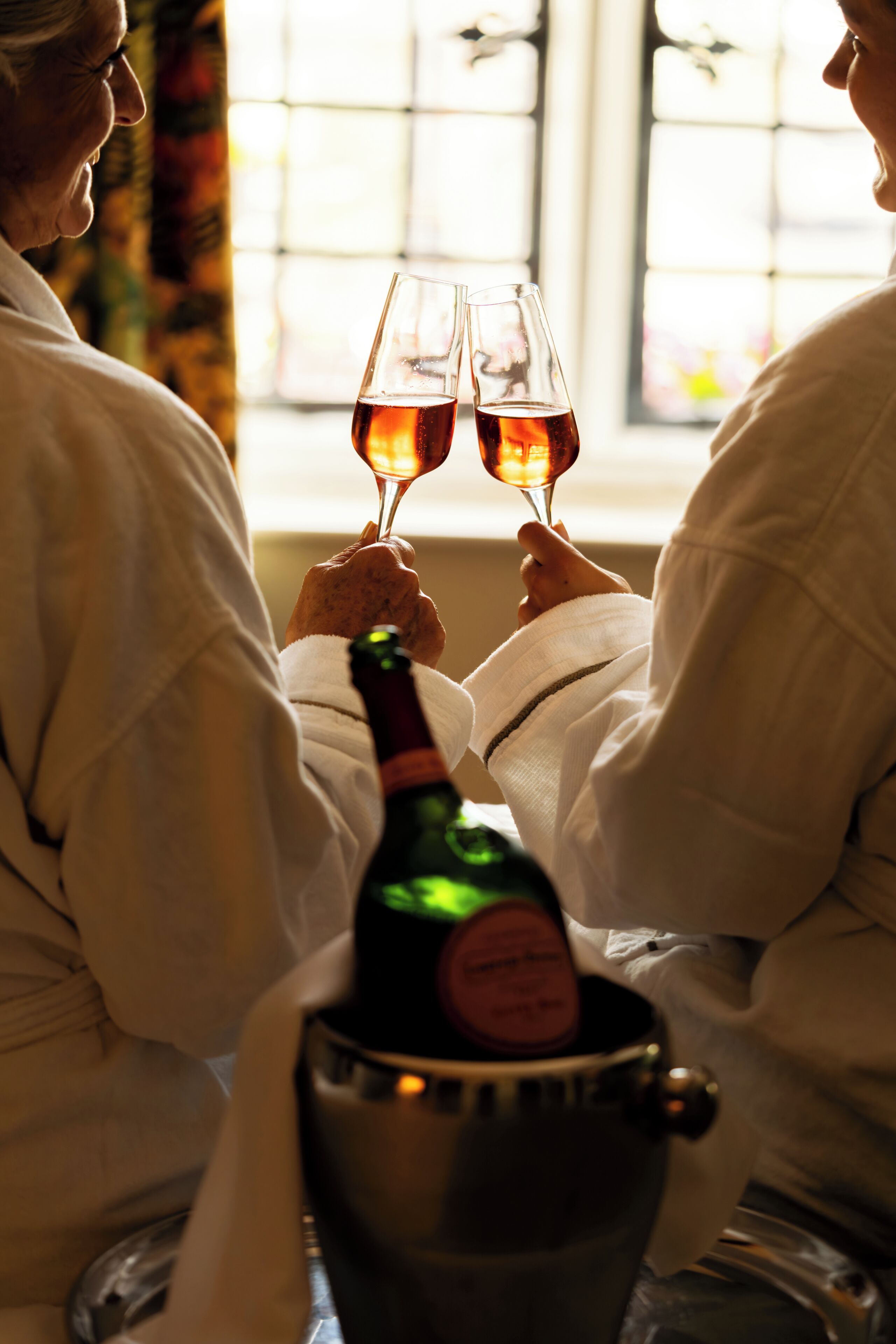 Two individuals seated at a table with a bottle of champagne in a bucket.