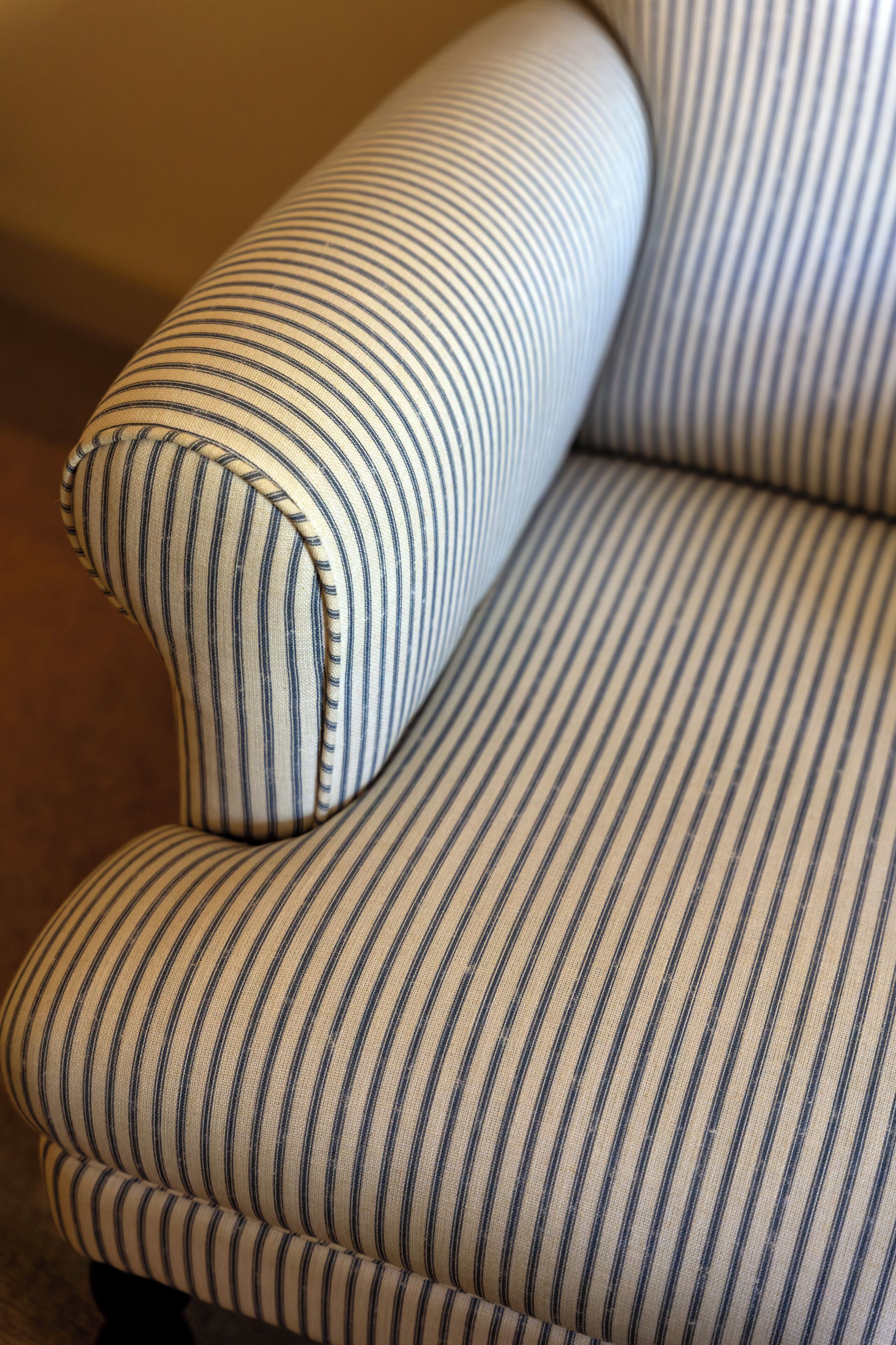 A striped sofa with a curved backrest and armrests.