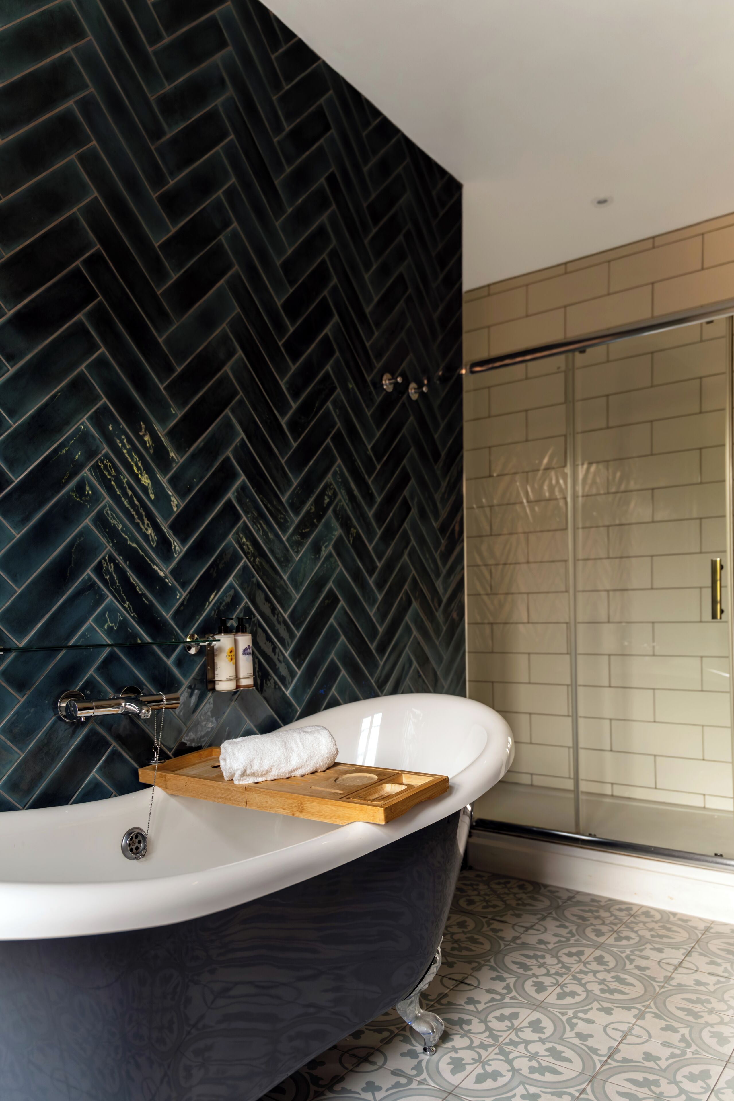 A modern bathroom with a freestanding bathtub, a wooden tray, and a towel.