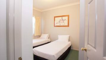 Ein Hotelzimmer mit zwei Einzelbetten, einem gerahmten Bild an der Wand und einer Tür mit Messinggriffen.
