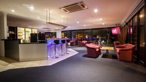 Zona de bar moderna con barra, taburetes y asientos.