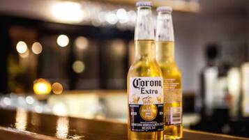 Two bottles of Corona Extra beer on a bar counter with a blurred background.