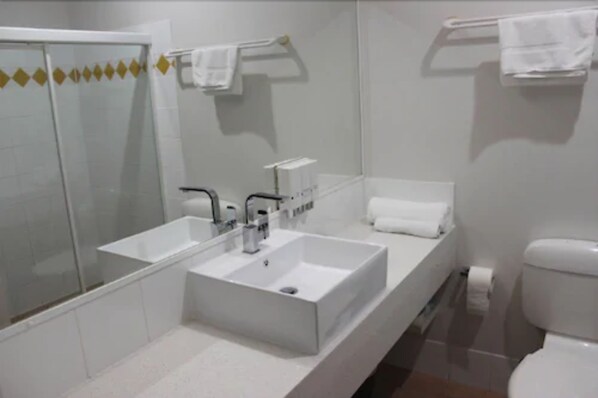 Un baño moderno con un espejo grande, lavamanos doble y un inodoro.