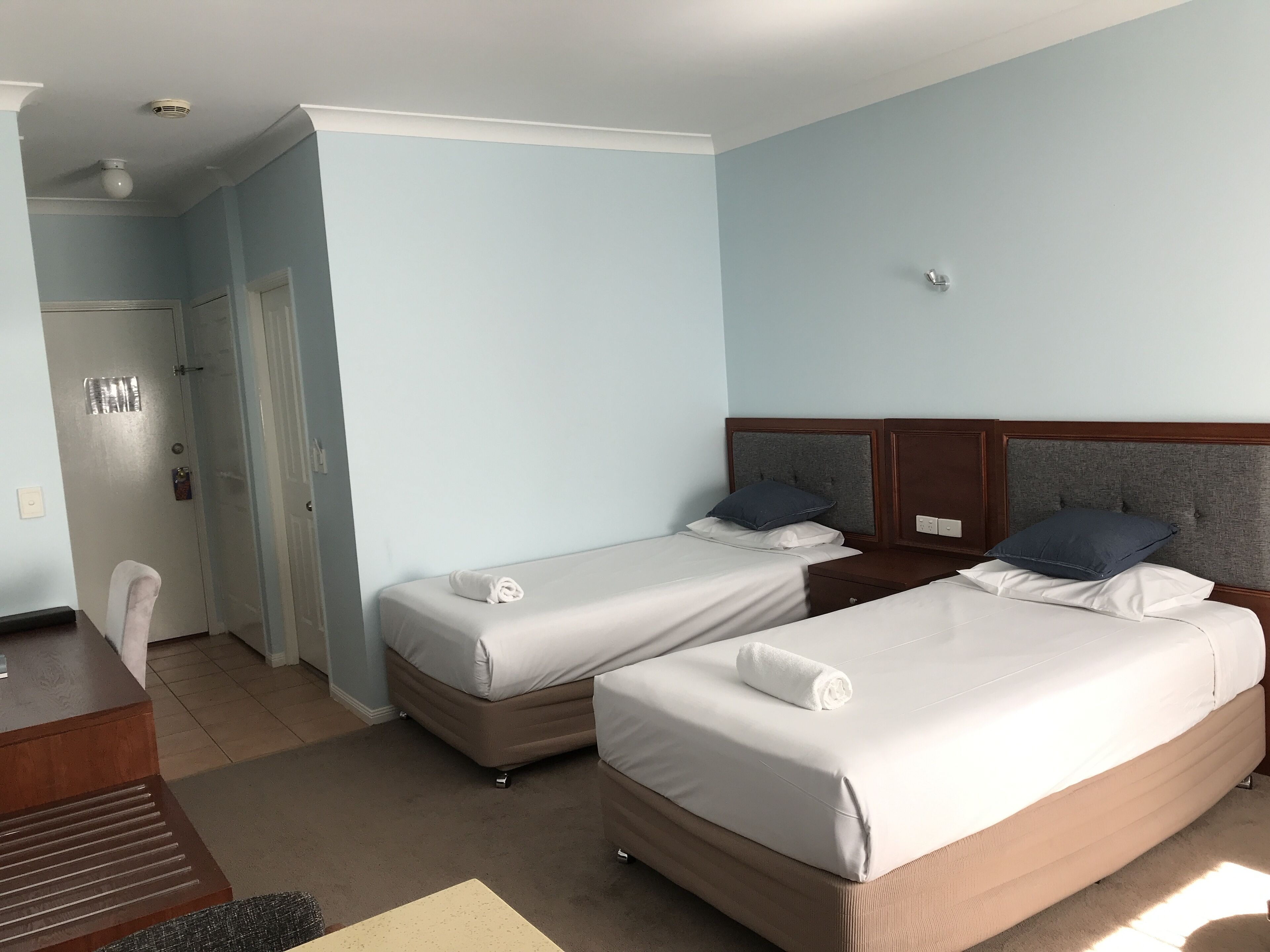 Habitación de hotel con dos camas, un escritorio y una silla.