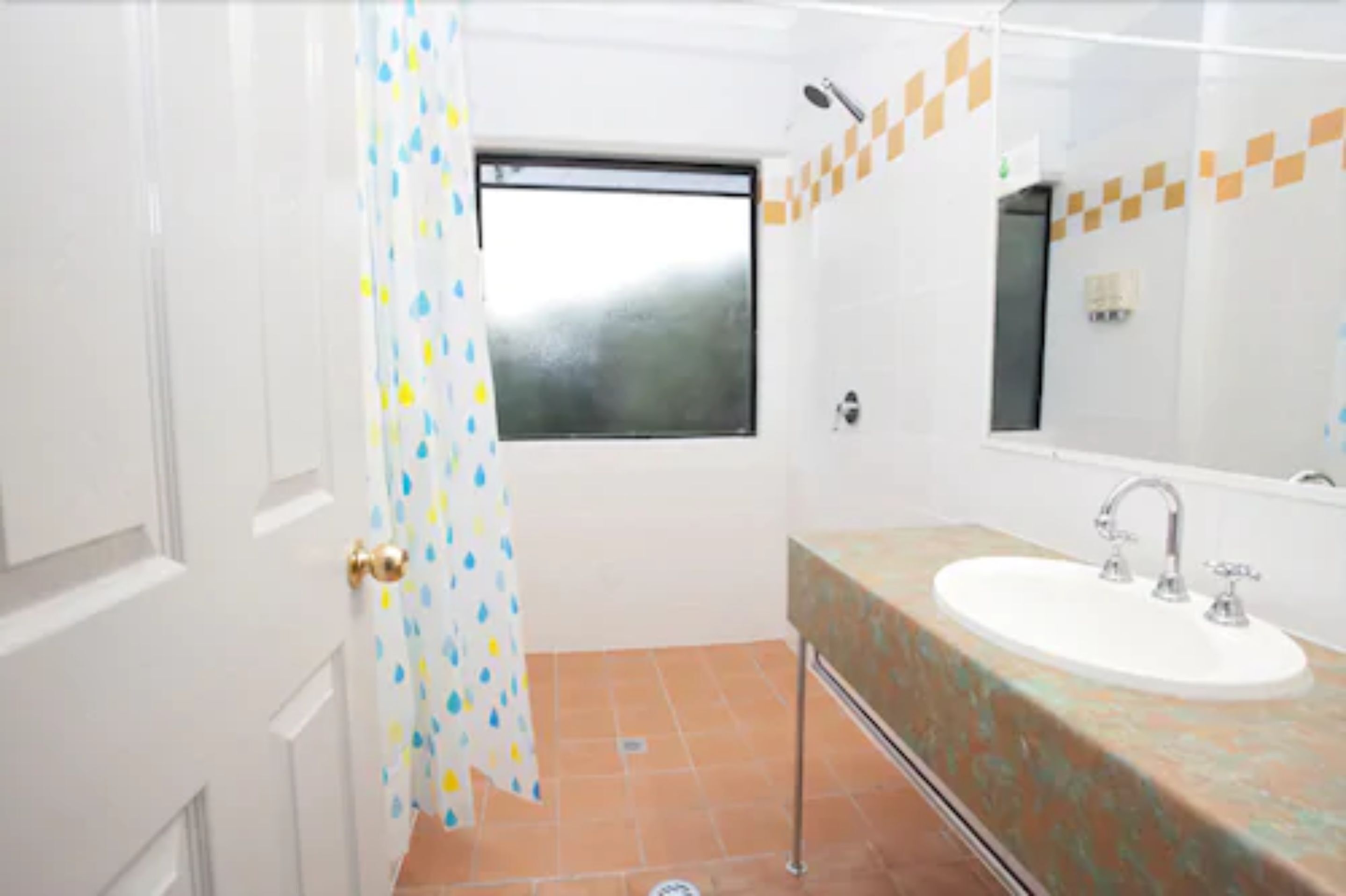 A bathroom with a white sink, a window, and a shower curtain.