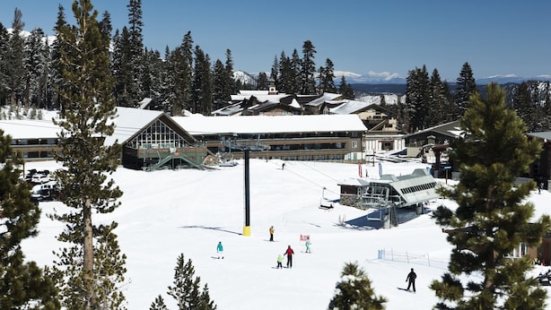 A ski resort with multiple buildings, a ski lift, and skiers on the slopes.