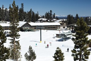 Une station de ski comprenant plusieurs bâtiments, un télésiège et des skieurs sur les pistes.