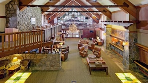 A spacious lobby with a high ceiling, stone walls, wooden beams, and a central chandelier.