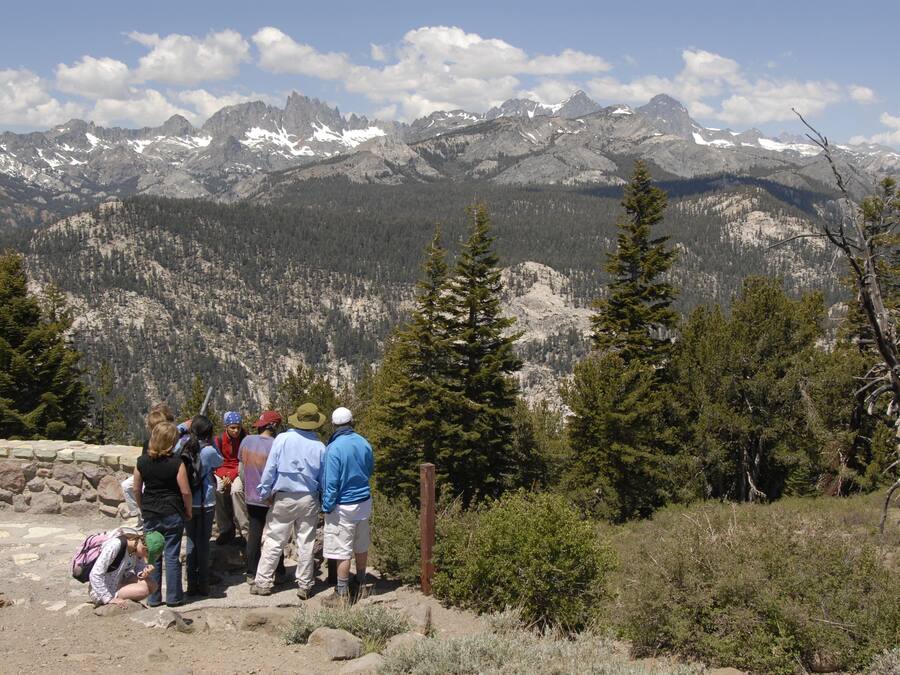 Un grupo de personas sobre un sendero rocoso, con montañas al fondo.