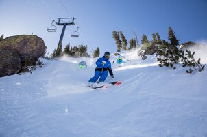 Una persona scia sulle piste innevate, con una seggiovia sullo sfondo.