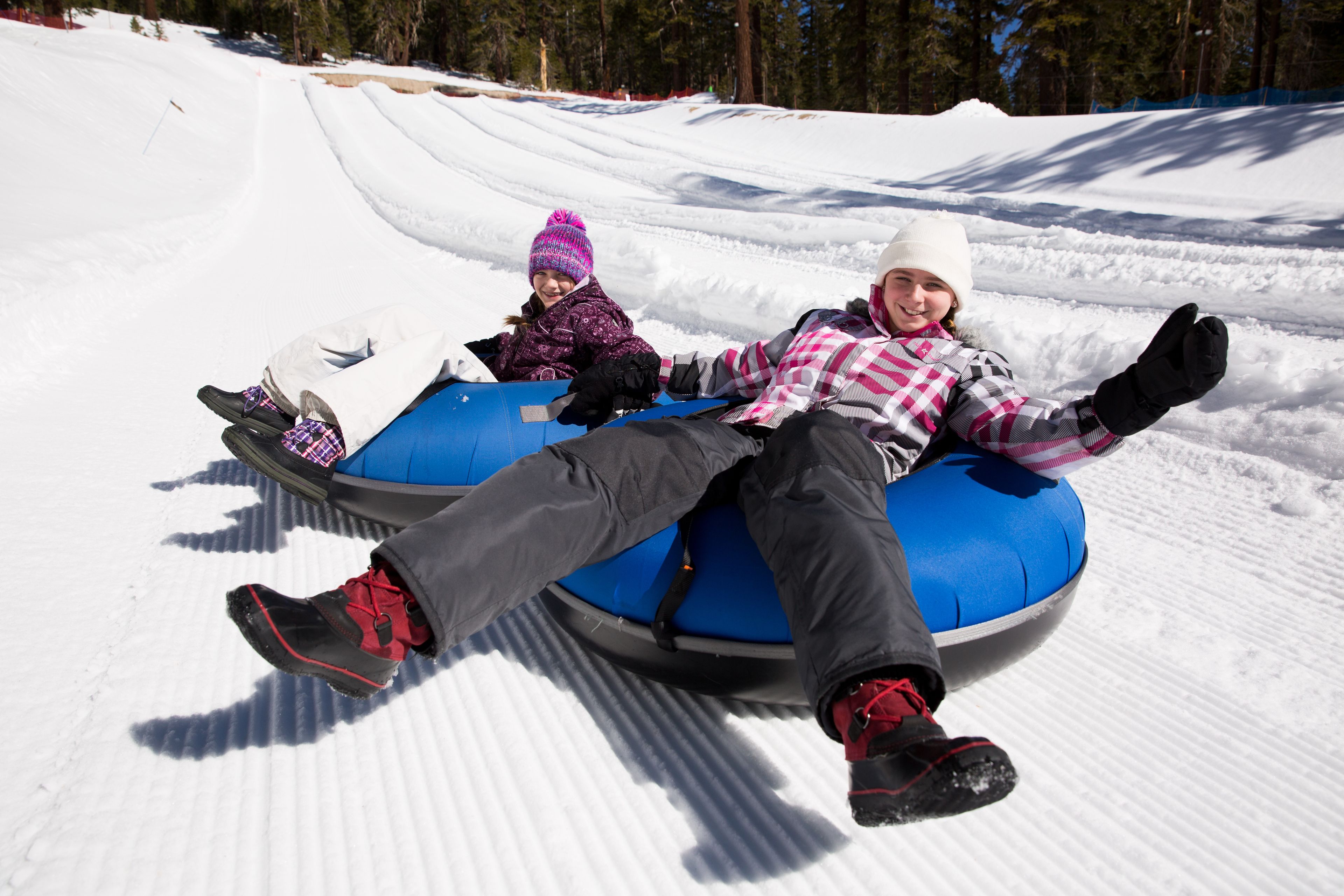 Two people on a blue sled on a snowy slope.