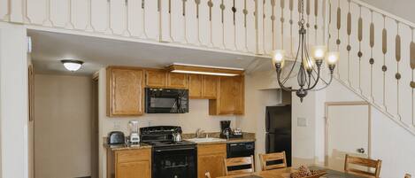 A kitchen with wooden cabinets, a stove, microwave, and a dining table with chairs.