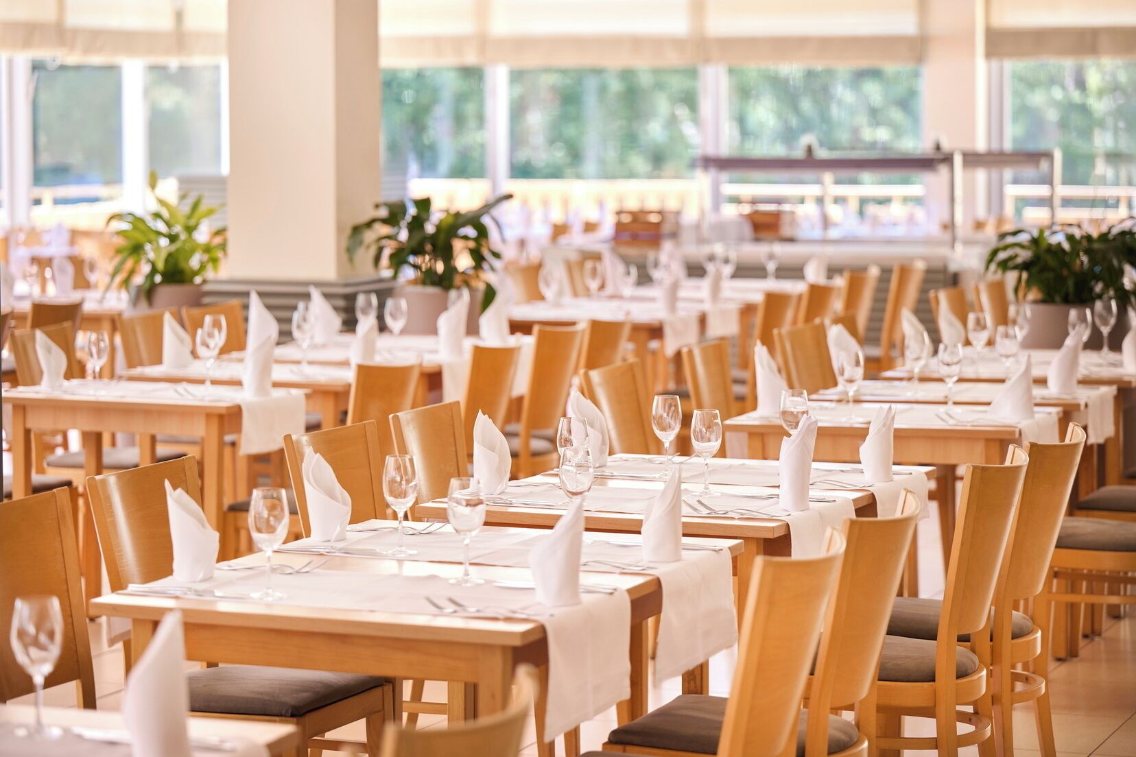 A spacious dining area with multiple tables and chairs, each set with white tablecloths and napkins.