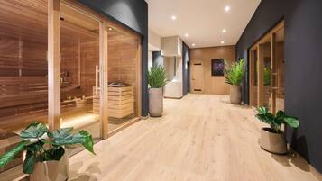 A modern interior with a wooden sauna, a massage table, and potted plants.