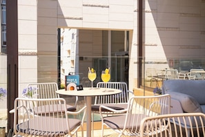 Een buitenzitgedeelte met een ronde tafel, stoelen en een boek met de titel 'TAKE A MINUTE'.