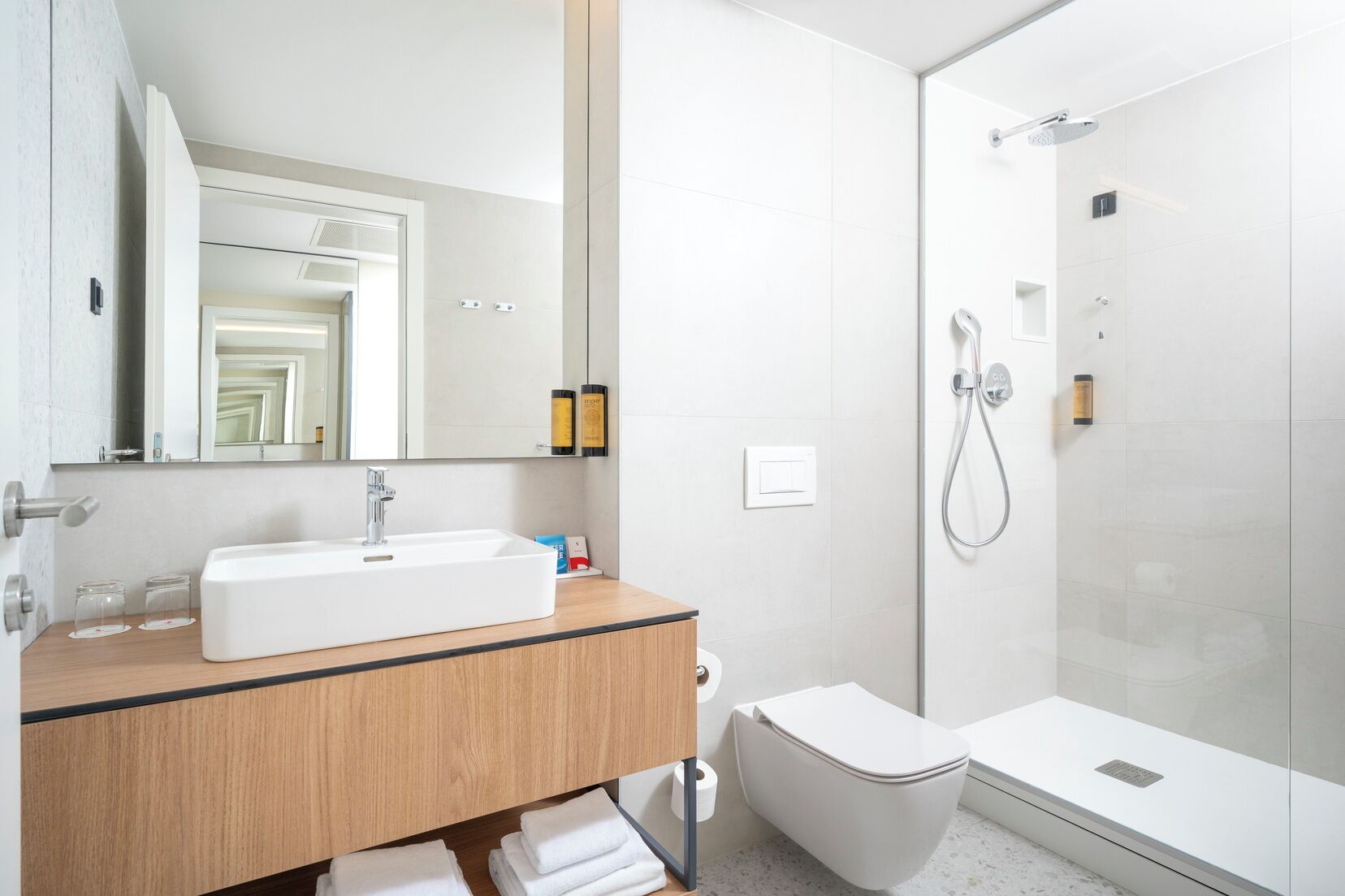 Ein modernes Badezimmer mit einem weißen Waschbecken, einem Spiegel und einer Dusche.