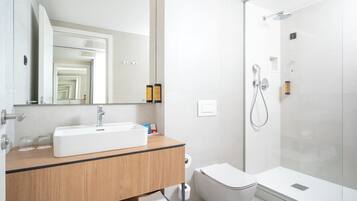 Ein modernes Badezimmer mit einem weißen Waschbecken, einem Spiegel und einer Dusche.