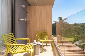 A balcony with yellow chairs and a small table, overlooking a terraced landscape.