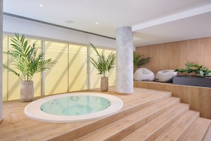 Un espace spa moderne doté d’un jacuzzi, d’un plancher en bois et de plantes en pot.