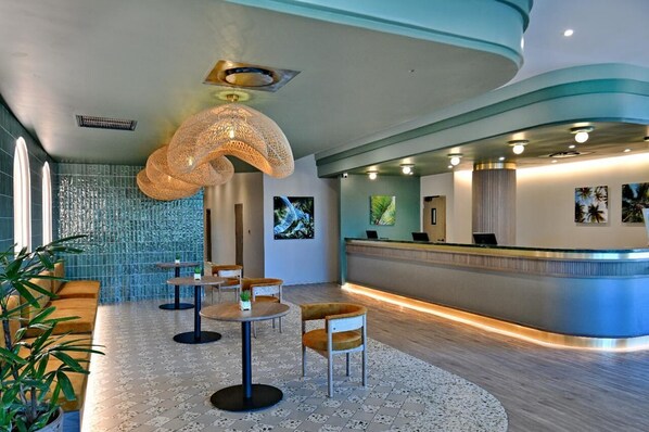 A modern reception area with a curved counter, seating arrangements, and artwork on the walls. - City Lodge Hotel Umhlanga Ridge (Umhlanga)
