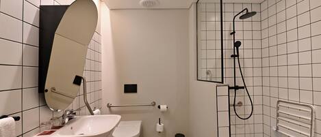 Un baño moderno con lavamanos, inodoro y ducha.
