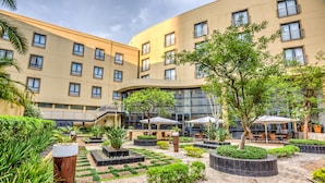A courtyard with a modern building, outdoor seating, and landscaped gardens. - City Lodge Hotel Umhlanga Ridge (Umhlanga)