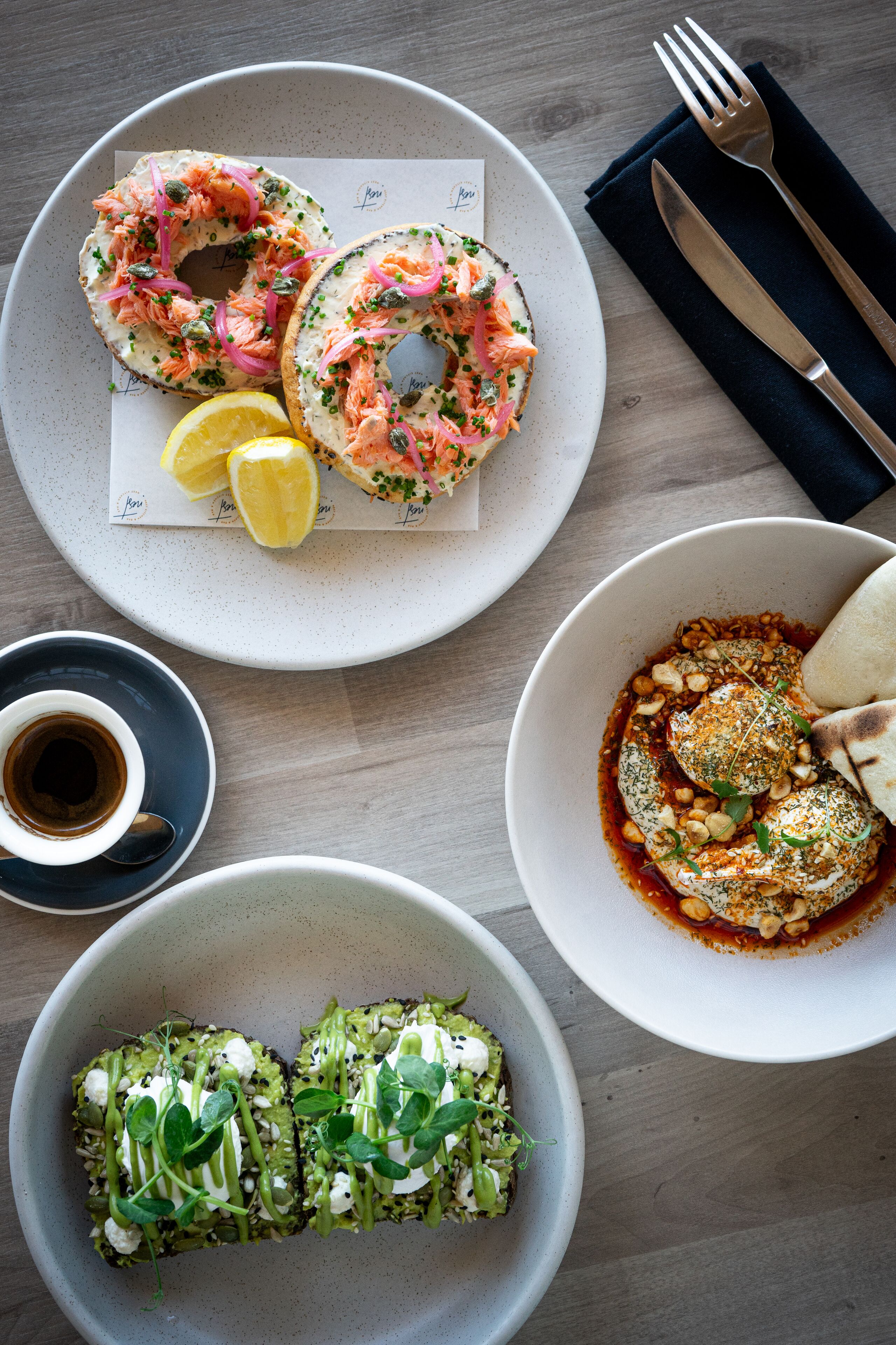 A table with a plate of bagels, a bowl of soup, and a cup of coffee.