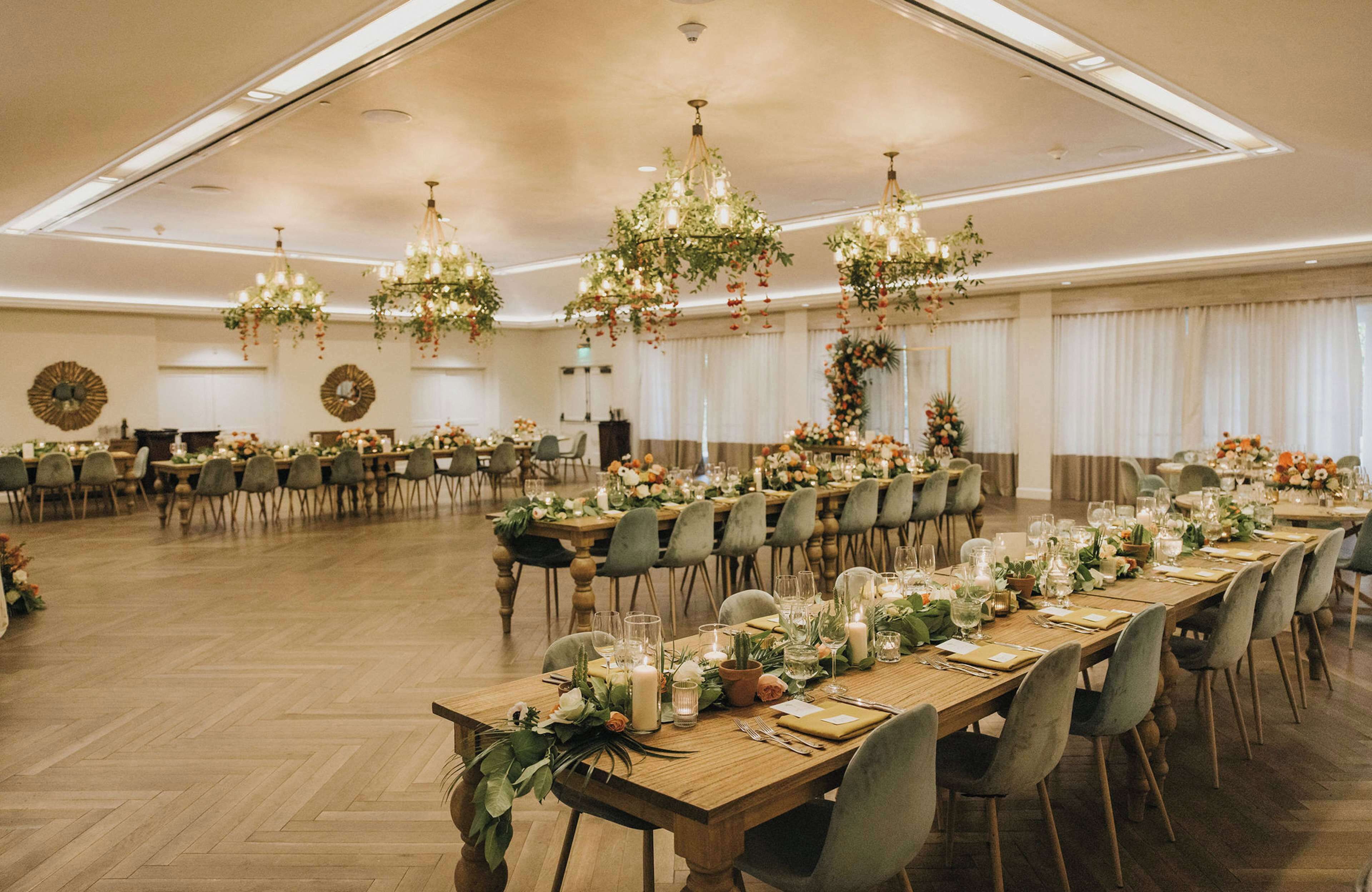 A banquet hall with long tables set for a formal event, adorned with floral centerpieces and candles.