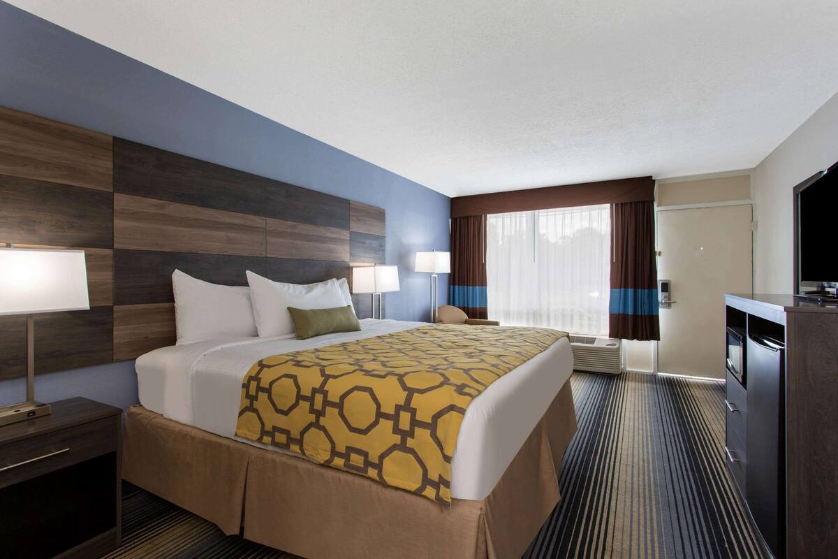A hotel room with a large bed, bedside tables, a desk, and a TV.