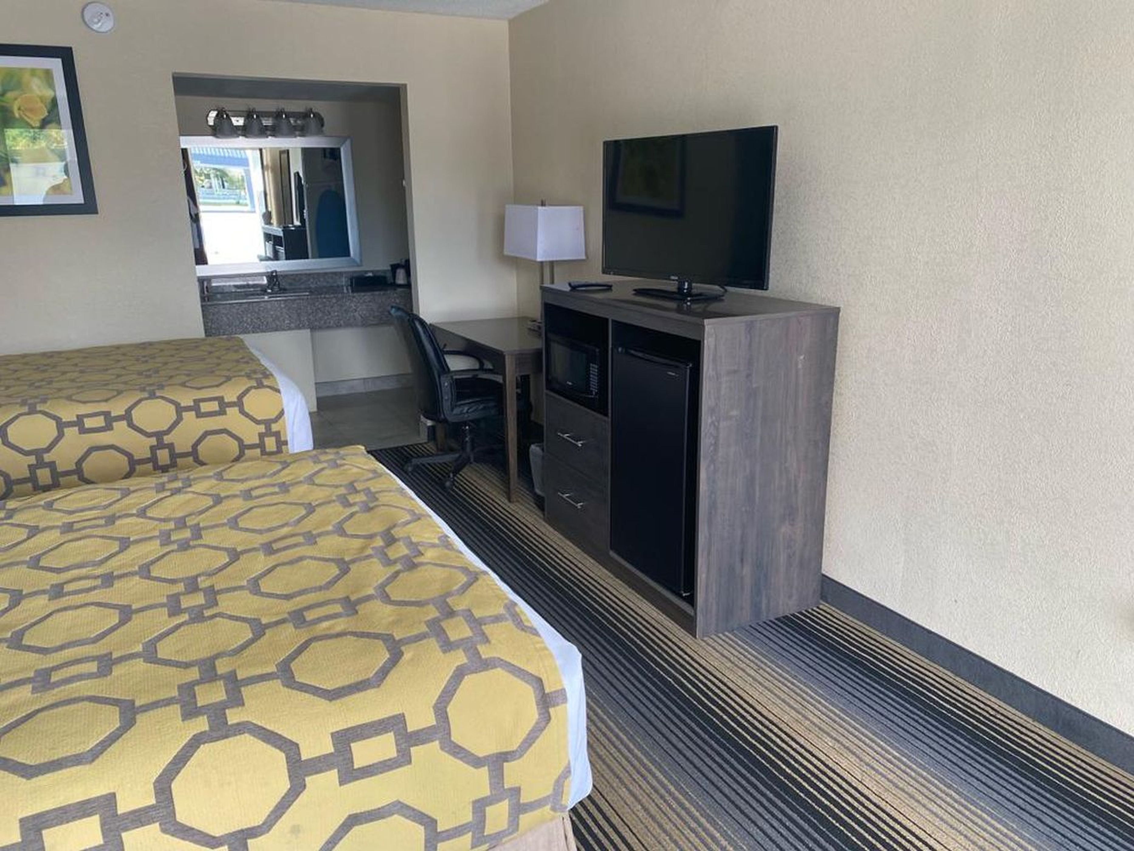 A hotel room with two beds, a desk, a television, and a minibar.