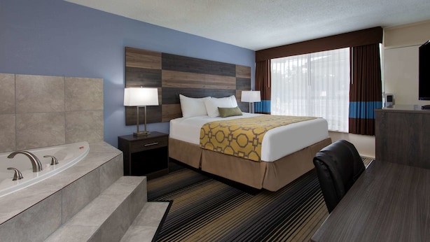 Habitación de hotel con una cama grande, baño con bañera, escritorio y televisión.