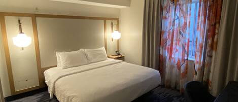 Een hotelkamer met een groot bed, twee bedlampen, een bureau en een stoel.