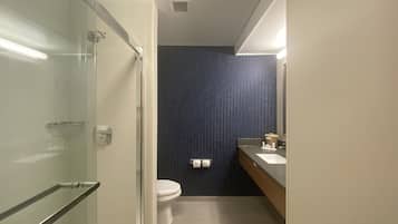 Un baño moderno con cabina de ducha de vidrio, inodoro y lavabo con espejo.