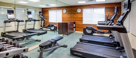 Academia com esteiras, aparelhos de musculação e um espelho grande.
