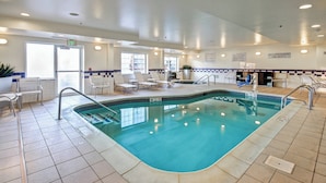 An indoor swimming pool with clear water, tiled walls, and a tiled floor. There are lounge chairs and a lifeguard chair near the pool. - Fairfield Inn & Suites by Marriott Saratoga Malta (Ballston Spa)