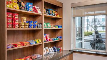 A snack display with various packaged foods and a window view of a statue.