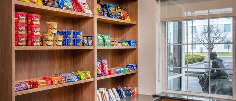 A snack display with various packaged foods and a window view of a statue.