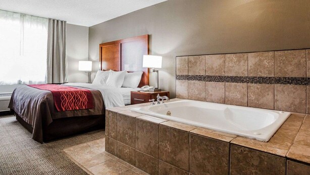 Une chambre d’hôtel dotée d’un grand lit, d’un coin salon séparé, d’une baignoire et offrant une vue sur l’extérieur.