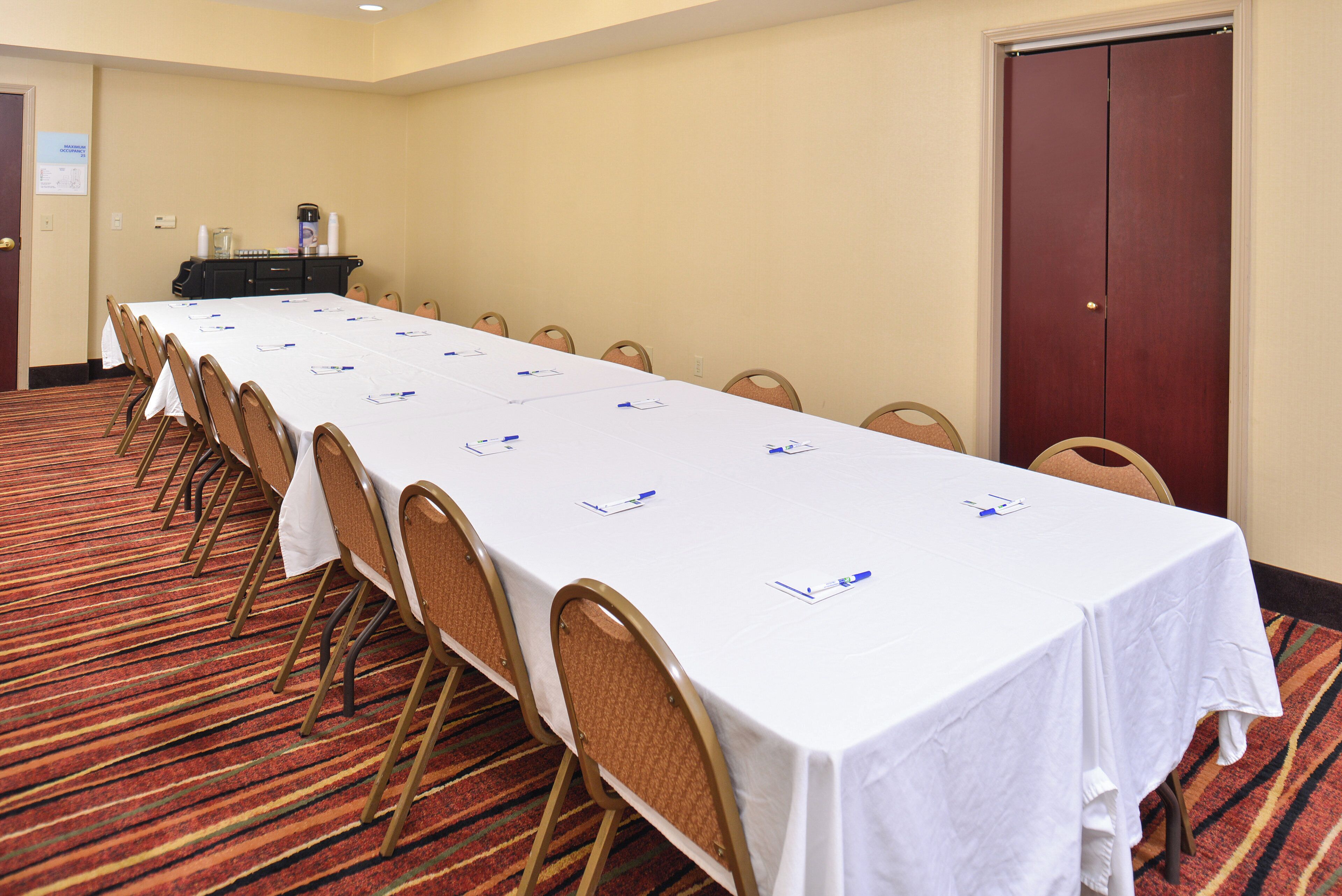 A conference room with a long table, chairs, and a carpeted floor.