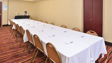 Una sala de conferències amb una taula llarga, cadires i un terra amb moqueta.