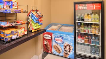 A snack display with various chips and instant food items, a Häagen-Dazs ice cream freezer, and a refrigerator stocked with beverages.