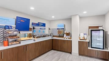 A breakfast bar with a variety of food options, including pastries, hot food, and a yogurt, eggs, and milk dispenser.