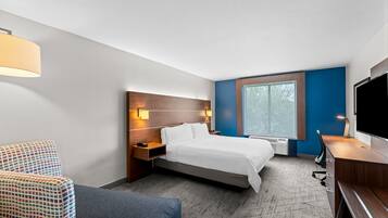 A hotel room with a bed, a desk, a TV, a chair, and a window.