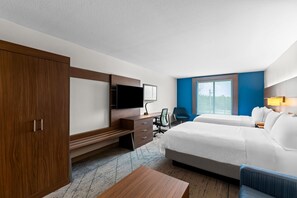 Quarto de hotel com uma cama grande, uma escrivaninha com televisão, uma cadeira e um guarda-roupa.