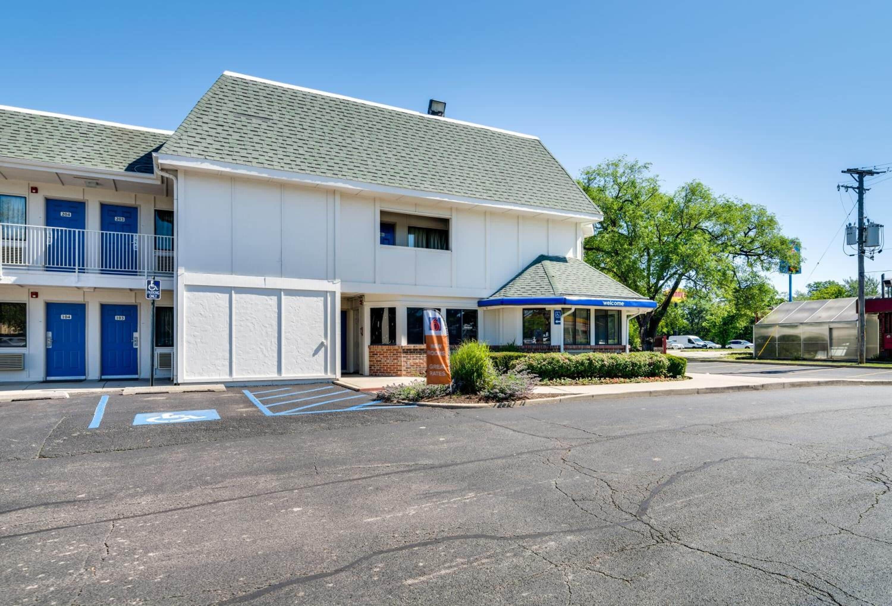 A two-story motel with blue doors, a covered front porch, and a parking lot with handicapped spaces.