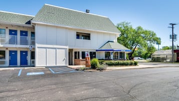 A two-story motel with blue doors, a covered front porch, and a parking lot with handicapped spaces.
