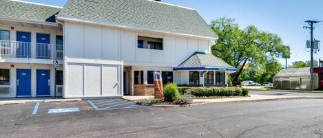 A two-story motel with blue doors, a covered front porch, and a parking lot with handicapped spaces.