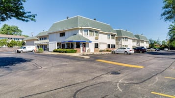 A hotel with a parking lot, a covered outdoor area, and a building with a green roof.